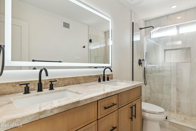 bathroom with a shower with door, vanity, and toilet