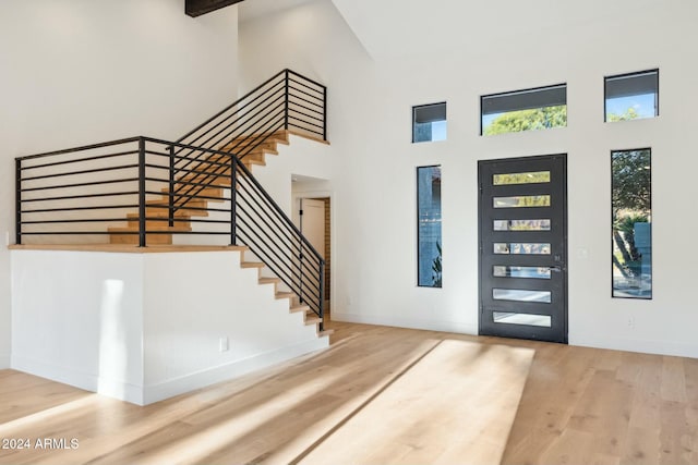 foyer with wood-type flooring and a towering ceiling