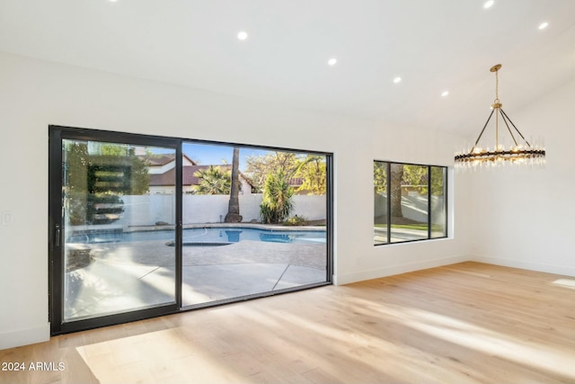 interior space featuring light wood-type flooring, an inviting chandelier, and lofted ceiling