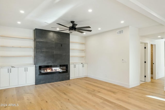 unfurnished living room featuring a fireplace, ceiling fan, and light hardwood / wood-style flooring