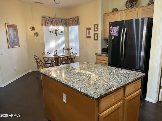 kitchen featuring black refrigerator, dark stone countertops, dark hardwood / wood-style flooring, a chandelier, and a center island