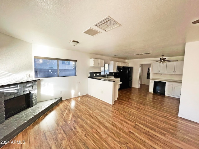 kitchen with white cabinetry, sink, a stone fireplace, dark hardwood / wood-style floors, and a textured ceiling