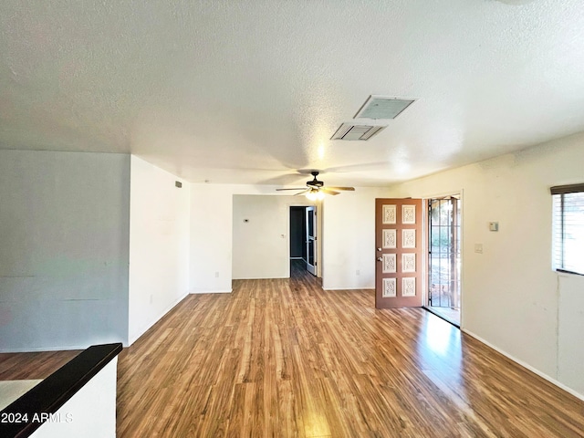 unfurnished living room featuring hardwood / wood-style flooring, ceiling fan, and a textured ceiling