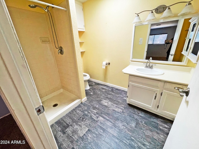 bathroom featuring vanity, toilet, and a tile shower