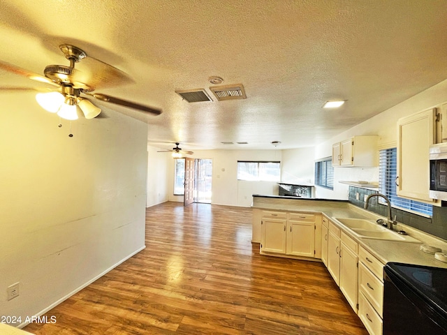 kitchen featuring a textured ceiling, light wood-type flooring, sink, and black range with electric cooktop