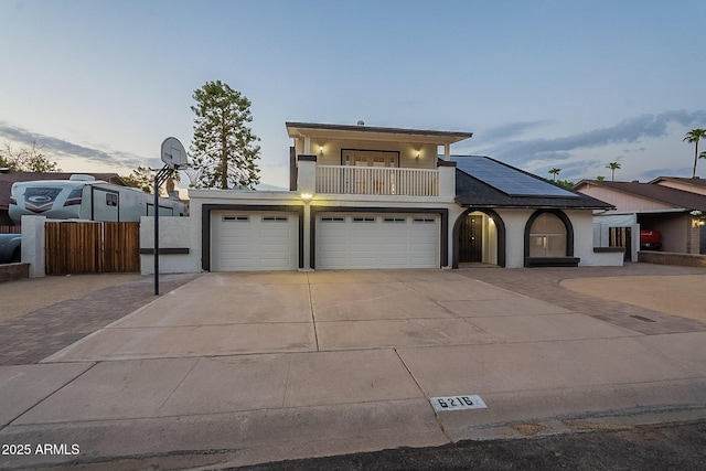 6216 W Poinsettia Dr, Glendale, AZ 85304 - view of front of house with driveway, a balcony, an attached garage, fence, and roof mounted solar panels
