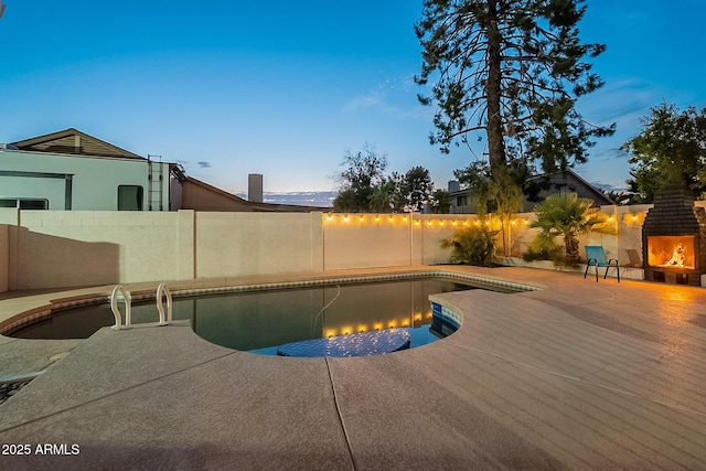 6216 W Poinsettia Dr, Glendale, AZ 85304 - pool at dusk with a fenced backyard, a warm lit fireplace, and a patio