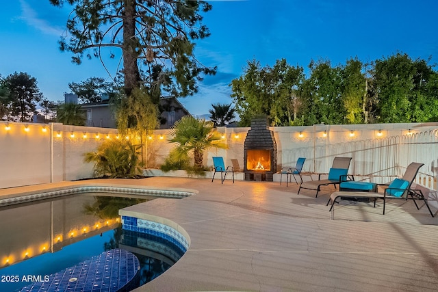 6216 W Poinsettia Dr, Glendale, AZ 85304 - pool at night with a lit fireplace, a patio, and a fenced backyard