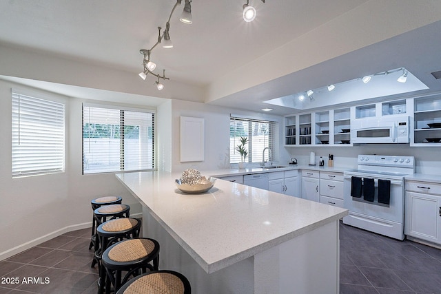 6216 W Poinsettia Dr, Glendale, AZ 85304 - kitchen with white appliances, a sink, dark tile patterned flooring, a breakfast bar, and a peninsula