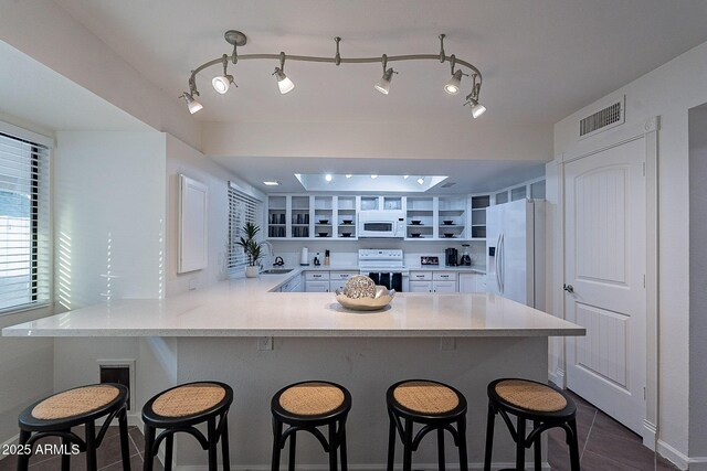 6216 W Poinsettia Dr, Glendale, AZ 85304 - kitchen featuring white appliances, a sink, a peninsula, light countertops, and a kitchen bar