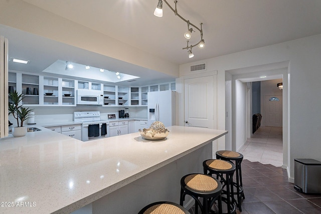 6216 W Poinsettia Dr, Glendale, AZ 85304 - kitchen featuring white appliances, open shelves, a peninsula, light stone countertops, and dark tile patterned flooring