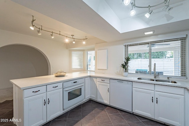6216 W Poinsettia Dr, Glendale, AZ 85304 - kitchen featuring white appliances, rail lighting, a sink, dark tile patterned floors, and a peninsula