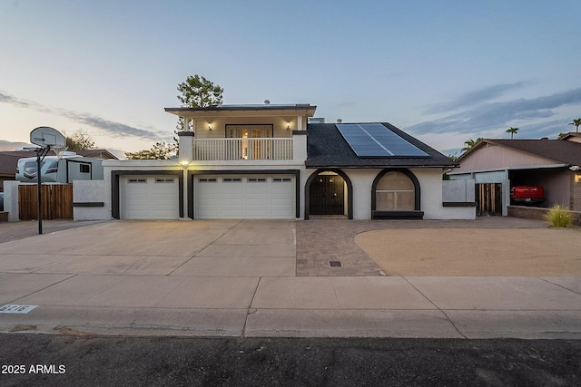6216 W Poinsettia Dr, Glendale, AZ 85304 - view of front of home featuring a balcony, concrete driveway, roof mounted solar panels, an attached garage, and stucco siding