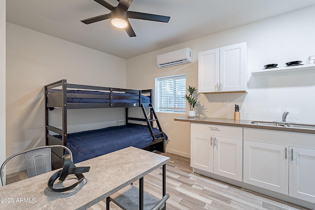 6216 W Poinsettia Dr, Glendale, AZ 85304 - bedroom featuring a wall unit AC, light wood-type flooring, a sink, baseboards, and ceiling fan