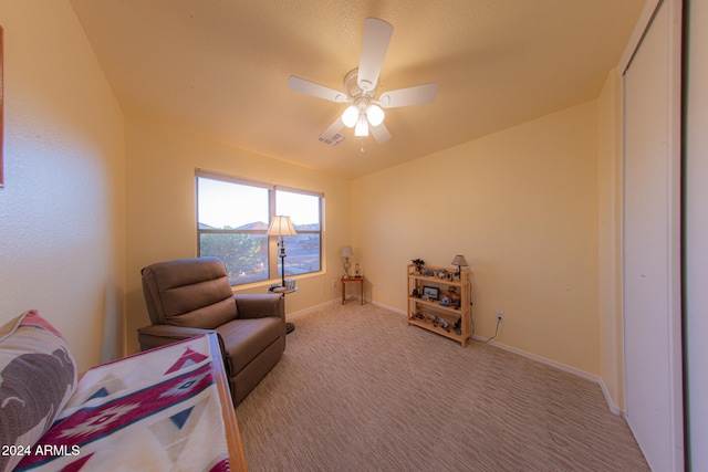 living area featuring light carpet and ceiling fan