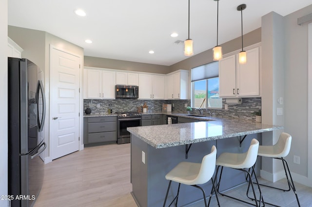 9750 E Radioactive Dr, Mesa, AZ 85212 - kitchen featuring appliances with stainless steel finishes, a peninsula, decorative backsplash, light wood finished floors, and white cabinets