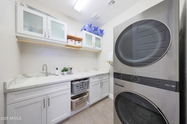 9750 E Radioactive Dr, Mesa, AZ 85212 - clothes washing area featuring stacked washer / drying machine, cabinet space, and light wood-style floors