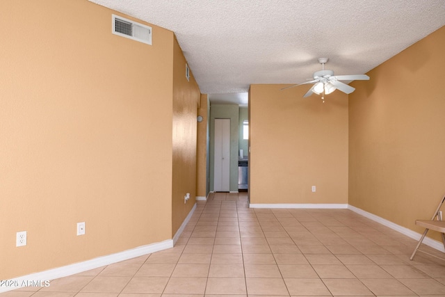 empty room featuring a textured ceiling, ceiling fan, and light tile patterned floors