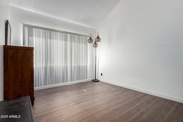 empty room featuring dark wood-type flooring and a textured ceiling