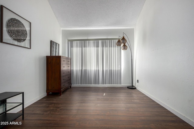 spare room featuring a textured ceiling and dark hardwood / wood-style flooring