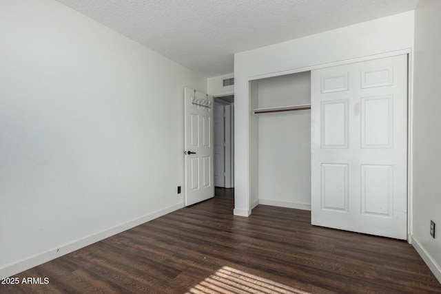 unfurnished bedroom with a closet, dark hardwood / wood-style flooring, and a textured ceiling