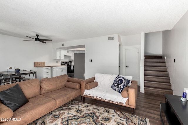 living room featuring ceiling fan, dark hardwood / wood-style floors, and a textured ceiling