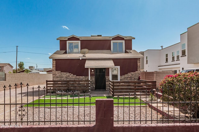 view of front of home with stone siding, stucco siding, and fence private yard