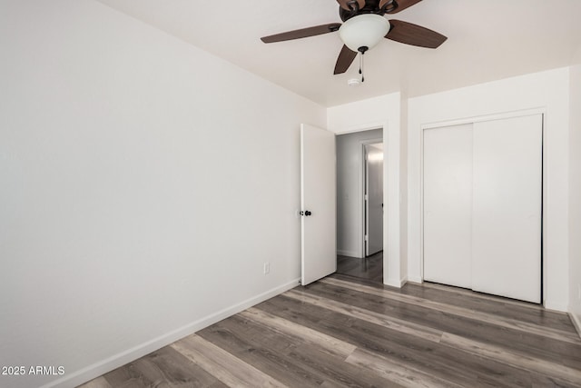 unfurnished bedroom featuring wood finished floors, baseboards, a closet, and ceiling fan