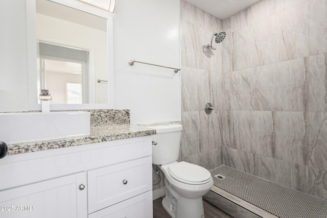 bathroom featuring vanity, toilet, and tiled shower