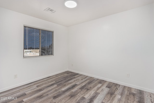 spare room featuring visible vents, baseboards, and wood finished floors