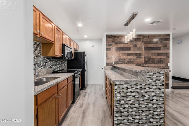 kitchen with light wood-type flooring, a sink, tasteful backsplash, black range with electric cooktop, and light stone countertops