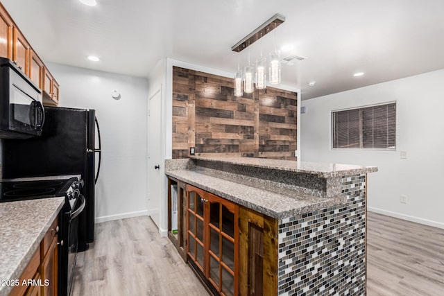 kitchen featuring brown cabinetry, light wood-style floors, black electric range oven, and hanging light fixtures