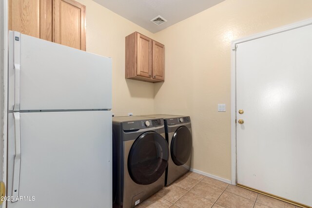 washroom featuring cabinets, light tile patterned flooring, and washer and dryer