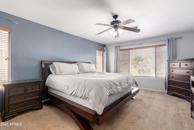 carpeted bedroom featuring multiple windows and ceiling fan