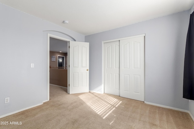 unfurnished bedroom with light colored carpet and a closet