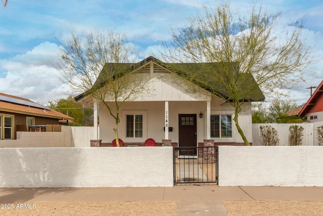 bungalow-style home with a fenced front yard, a porch, stucco siding, and a gate