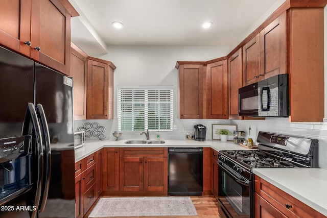 kitchen featuring brown cabinets, black appliances, a sink, light countertops, and decorative backsplash