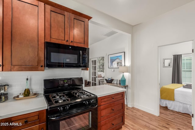 kitchen featuring decorative backsplash, black appliances, light wood-style flooring, and light countertops