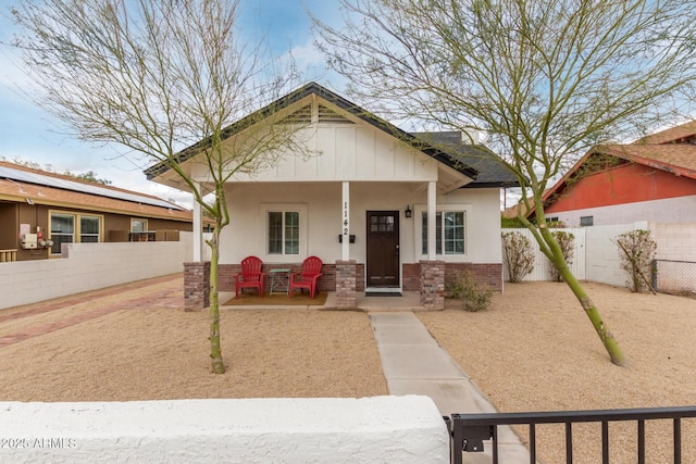 view of front of property featuring brick siding, a porch, fence private yard, and a gate