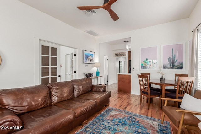 living room featuring light wood-type flooring, visible vents, ceiling fan, and french doors