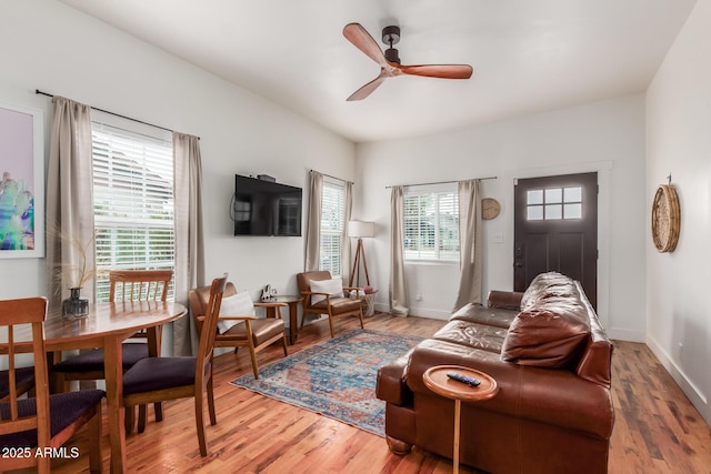 living area with baseboards, ceiling fan, and wood finished floors