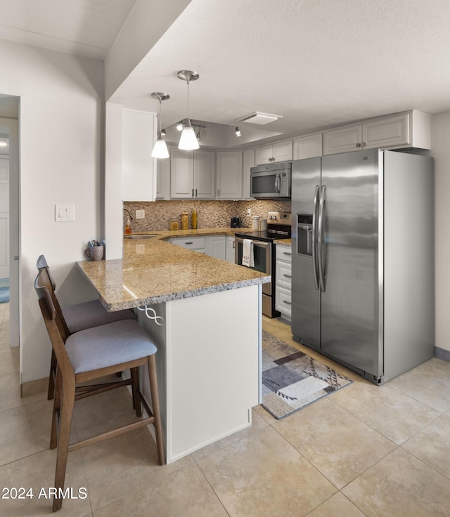 kitchen with kitchen peninsula, stainless steel appliances, gray cabinets, and hanging light fixtures