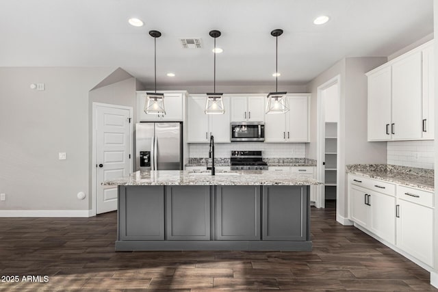 kitchen with sink, an island with sink, pendant lighting, stainless steel appliances, and white cabinets