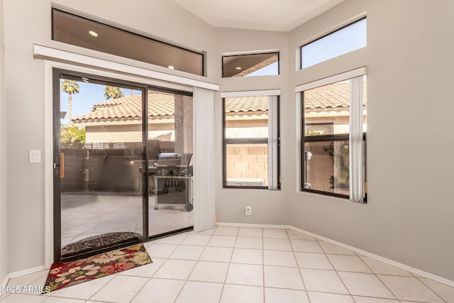 doorway with light tile patterned flooring and lofted ceiling