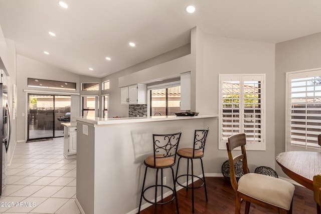 kitchen featuring white cabinetry, lofted ceiling, a kitchen bar, and kitchen peninsula