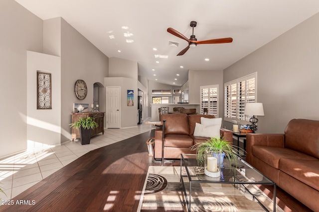 tiled living room featuring ceiling fan and high vaulted ceiling