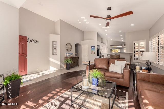 living room featuring ceiling fan, a towering ceiling, and light hardwood / wood-style floors