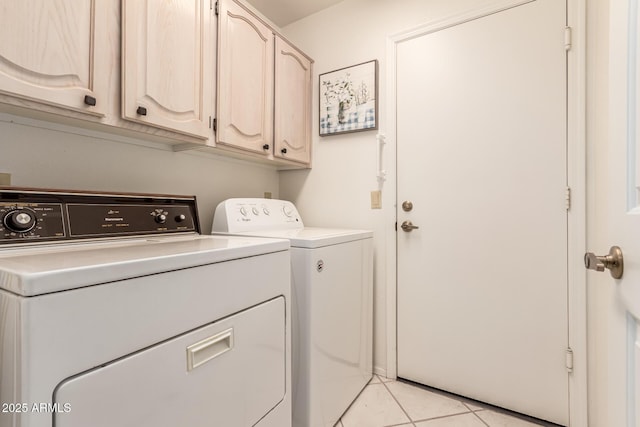 clothes washing area featuring cabinets, light tile patterned floors, and washing machine and clothes dryer