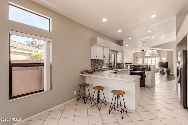 kitchen with sink, a breakfast bar, appliances with stainless steel finishes, white cabinets, and kitchen peninsula