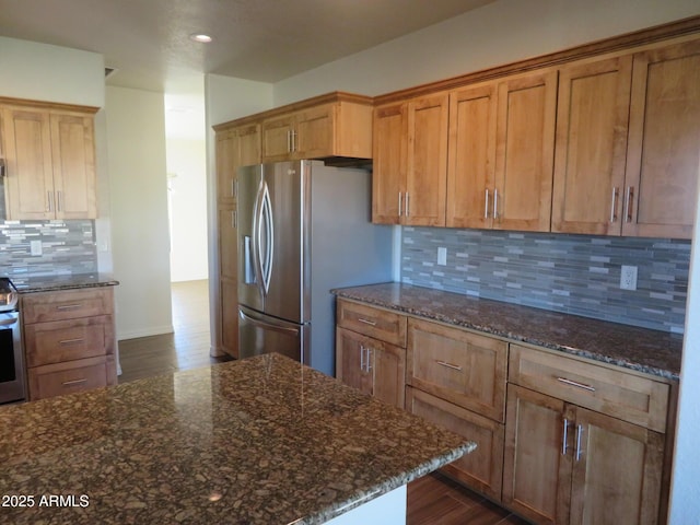 kitchen with stainless steel appliances, tasteful backsplash, and dark stone counters